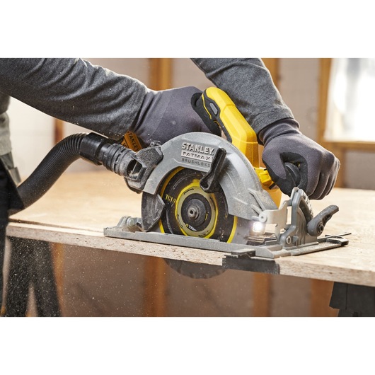 STANLEY SFMCS551M1T circular saw cutting wood, close-up, with brushless motor and dust extraction hose.