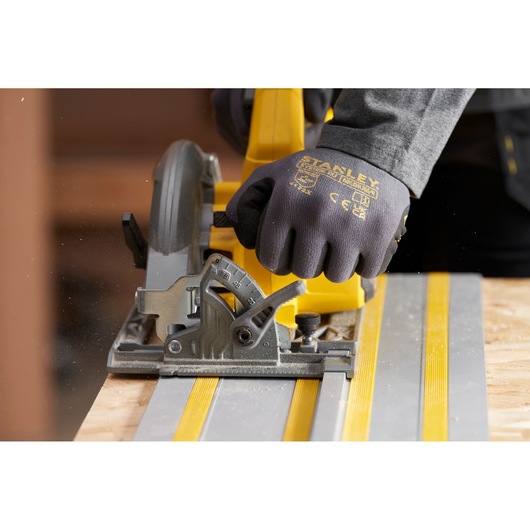 STANLEY SFMCS551M1T circular saw on guide track, close-up photo showing gloved hand and saw controls.