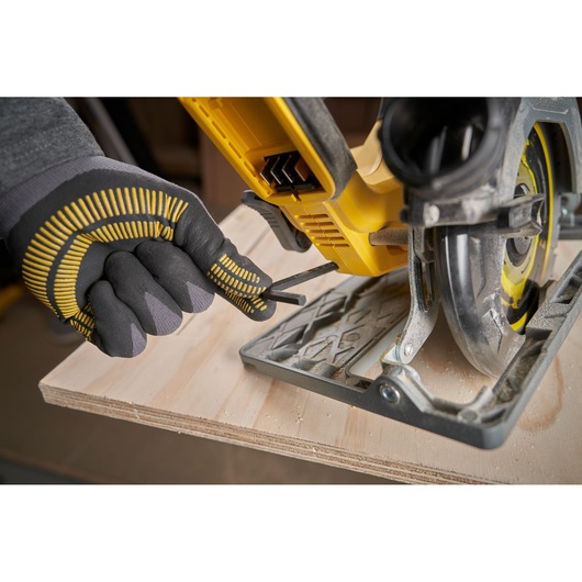STANLEY SFMCS551M1T circular saw close-up with gloved hand adjusting base on plywood.