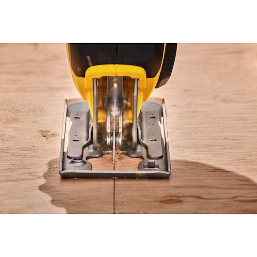 STANLEY SFMCS600M2K jigsaw cutting wood, close-up front angle, yellow and black tool, photography.
