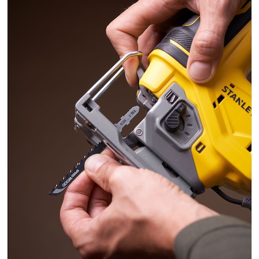 STANLEY SFMCS650B 18V brushless jigsaw close-up showing blade installation, yellow and black body, handheld.