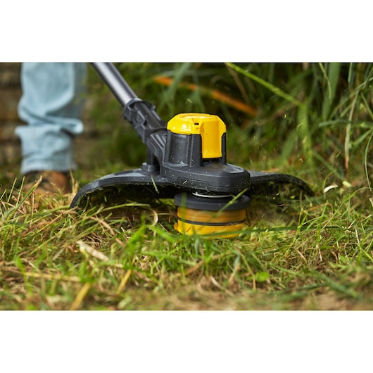 STANLEY SFMCSTB933B grass trimmer in use cutting grass, close-up of trimmer head outdoors.