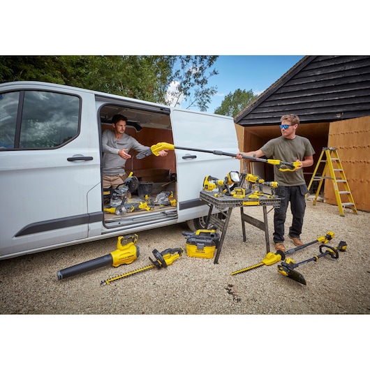 STANLEY SFMCSTB933B power tools displayed near work van, on table and ground, outdoor setting.