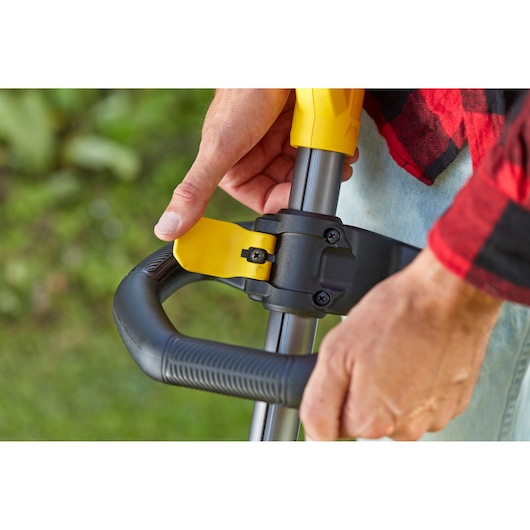 STANLEY SFMCSTB933M trimmer adjustable handle close-up, showing yellow lever and black grip outdoors.