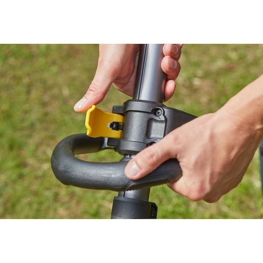 Photo of STANLEY SFMCSTB963B grass trimmer handle adjustment with yellow lever in outdoor setting.