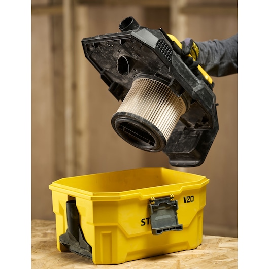 STANLEY V20 vacuum filter and lid being lifted from a yellow vacuum body in a workshop setting.