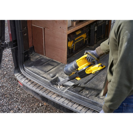 Photo of STANLEY SFMCVS001D1 cordless handheld vacuum in use on a van floor, yellow and black design.