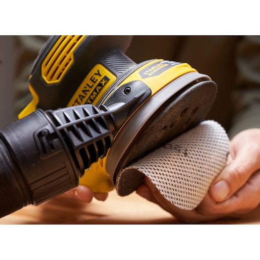 STANLEY SFMCW220D1S sander close up with sanding pad held by hand