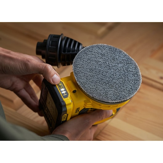 STANLEY SFMCW220D1S cordless sander in use on wood surface, close-up side view.