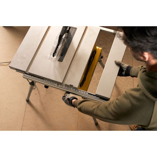 STANLEY SST1800 table saw photography, top view with gloved hands adjusting fence.