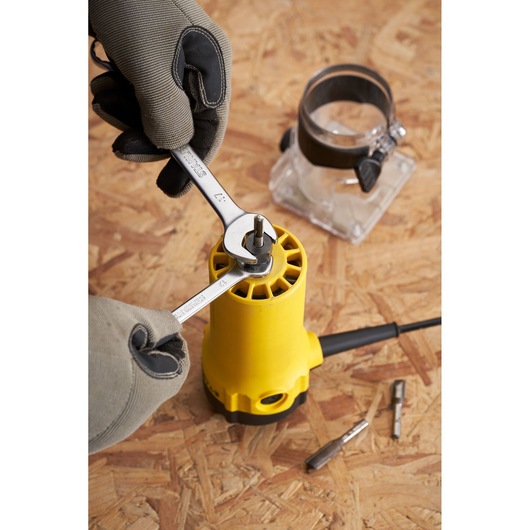 STANLEY ST55 router assembly with wrenches and gloved hands, close-up on tool and accessories on wood surface.