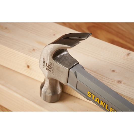 STANLEY STHT0-51309 claw hammer with steel head and grey handle on wooden boards, close-up.