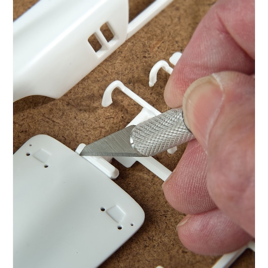 STANLEY STHT0-73872 precision hobby knife cutting white plastic model parts, close-up photography.