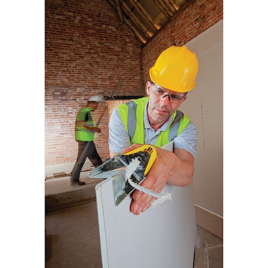 STANLEY STHT1-05937 hand tool for cutting drywall, shown in use on construction site.
