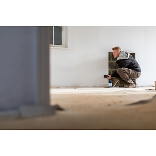 STANLEY STHT1-77139 laser distance measurer in use for measuring a wall in a room during construction.