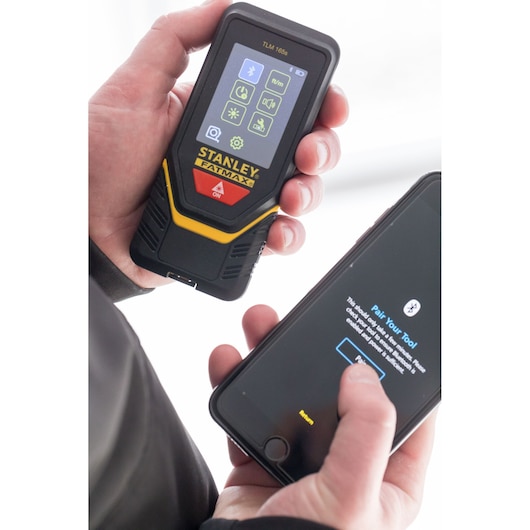 STANLEY STHT1-77139 laser distance measurer held in hand, pairing with smartphone via Bluetooth.