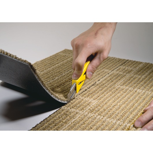 STANLEY STHT10265-0 utility knife cutting beige carpet, close-up hand use, product photography.