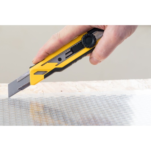 Photo of STANLEY STHT10268-1 utility knife cutting material, yellow and black handle, side angle.