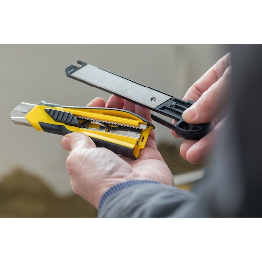 Photo of STANLEY STHT10270-0 utility knife being loaded with replacement blades, held in hands.
