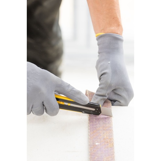 Stanley STHT10345-0 utility knife cutting material, photo shows gloved hands using tool.