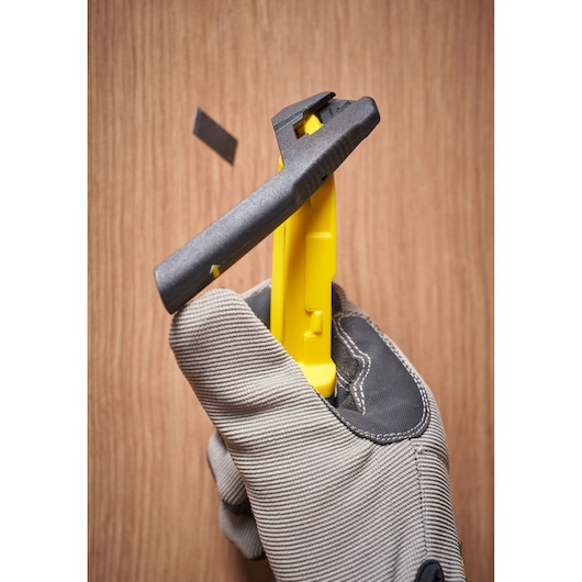 STANLEY STHT10500-0 yellow and black utility knife in gloved hand ejecting blade, close-up.