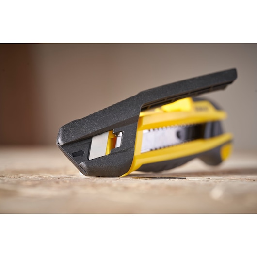 STANLEY STHT10501-0 utility knife with yellow and black body, close-up side angle on a wooden surface.