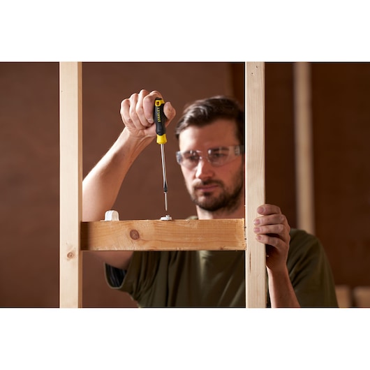 STANLEY STHT16146-0 screwdriver used on a wooden frame, close-up photography in construction setting.