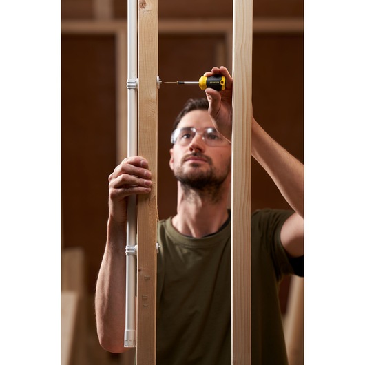 Photo of STANLEY STHT16154-0 screwdriver used to fasten screw in wood frame, indoor construction setting.