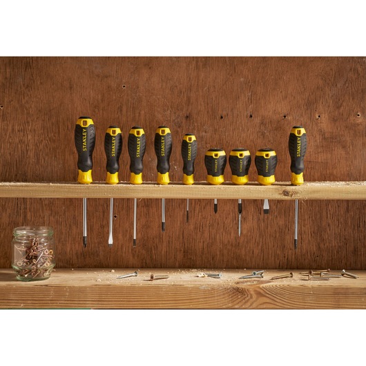 STANLEY STHT16195-0 screwdriver set with black and yellow handles, lined up on a wooden shelf, front view.