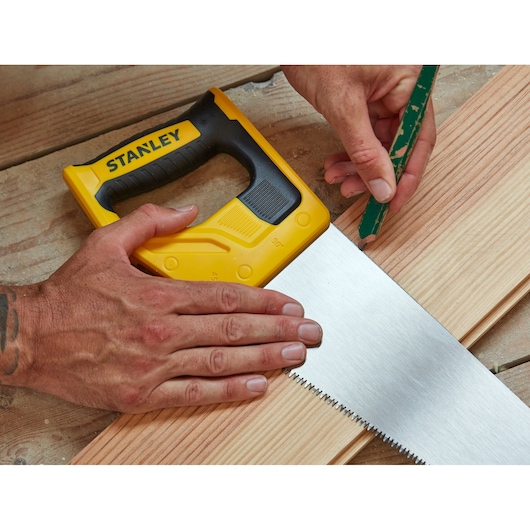 Photo of STANLEY STHT20354-1 hand saw, yellow handle, used to mark wood plank on workbench.