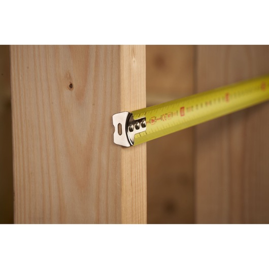 STANLEY STHT36804-1 tape measure in use, close-up of yellow blade measuring wooden beam.