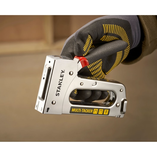 Stanley STHT6-70410 multi-tacker stapler held in gloved hand, close-up side angle.