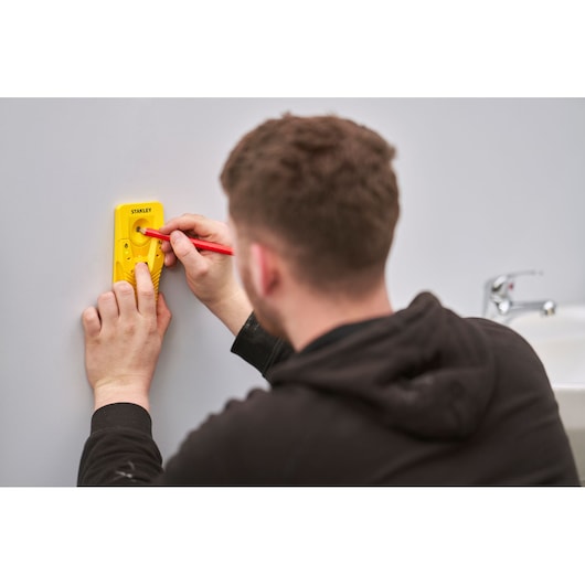STANLEY STHT77587-0 digital stud finder in use on wall near sink, yellow handheld device, photography.