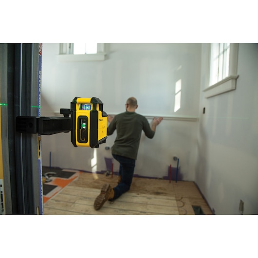 STANLEY STHT77594-1 laser level in use, mounted on wall, construction professional aligning wall trim.