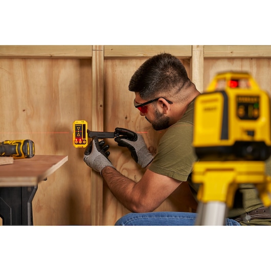 STANLEY STHT77616-0 laser detector in use for wall leveling, shown with gloves and laser level equipment.