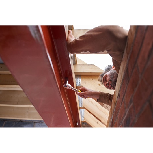 Photo of STANLEY STMT82831-1 ratchet in use tightening a bolt on a steel beam at a construction site.