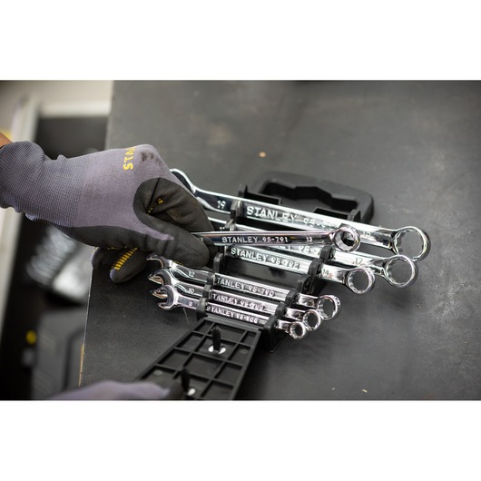 STANLEY STMT82842-0 chrome combination wrenches in holder, hand with glove selects tool, angled view.
