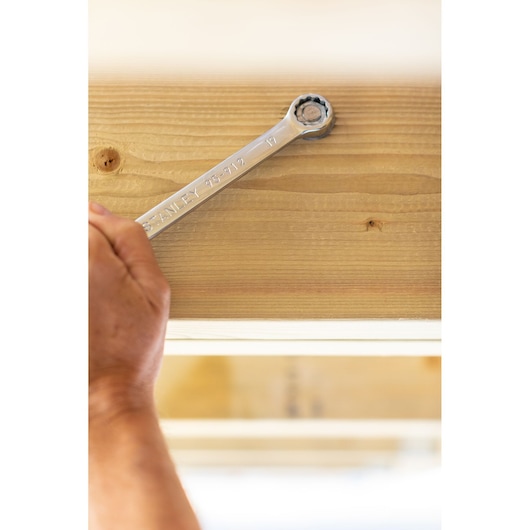 Photo of STANLEY STMT82842-0 ratcheting wrench tightening a bolt on light wood surface.