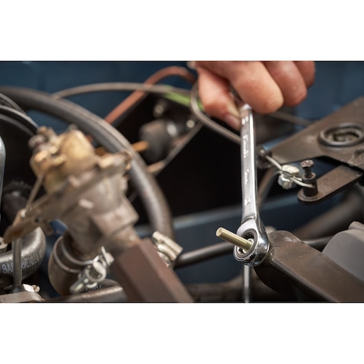 Photo of STANLEY STMT82846-0 flat ratcheting wrench in use tightening a bolt on machinery, part of 7-piece set.