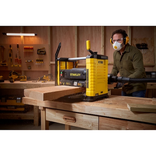 STANLEY STP18-B2 benchtop planer in use on wooden board, workshop setting, front angle.