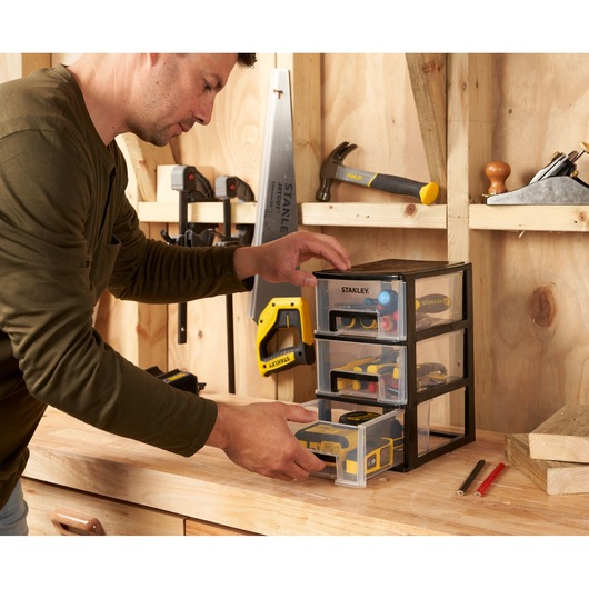 STANLEY STST40711-1 small parts organizer with three clear drawers on a workbench in a workshop.