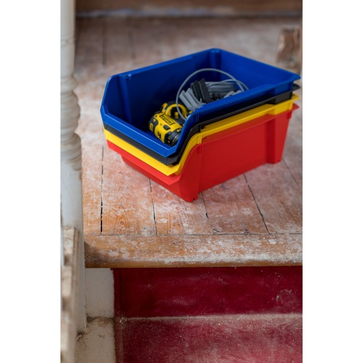 STANLEY STST82745-1 stackable storage bins in red, yellow, and blue with tools on wooden floor.