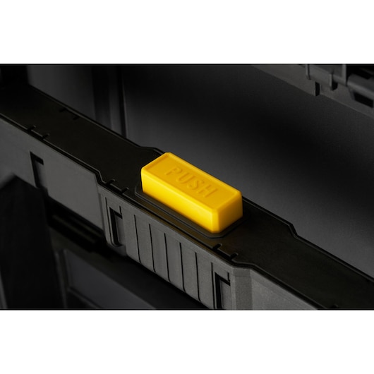 STANLEY STST83319-1 toolbox close-up with a yellow push button, front angle, black surface.