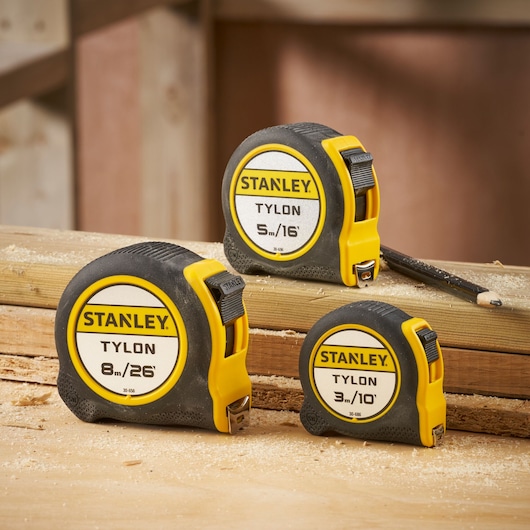 STANLEY 0-30-686 tape measures with yellow and black casing, displayed on a wooden workbench.