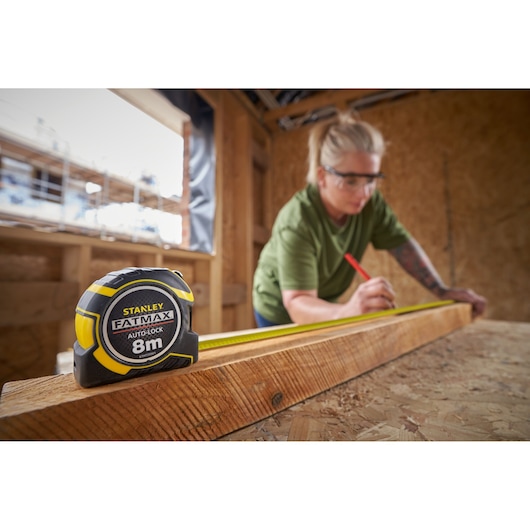 STANLEY XTHT0-33501 tape measure, FatMax 8m, photography of product in use for measuring wood.