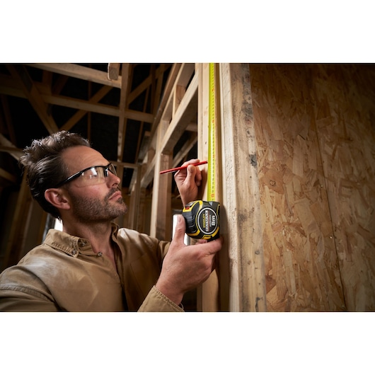 Photo of STANLEY XTHT0-33501 tape measure used to measure wooden frame during construction.