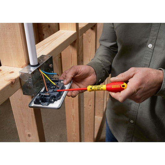 Photo of STANLEY XTHT0-62692 insulated screwdriver in use on electrical outlet wiring, close-up.