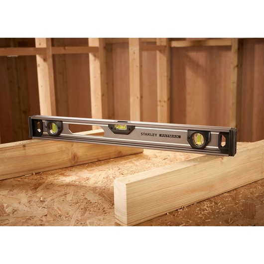 STANLEY XTHT1-42131 spirit level on wood beams in construction setting, side angle.