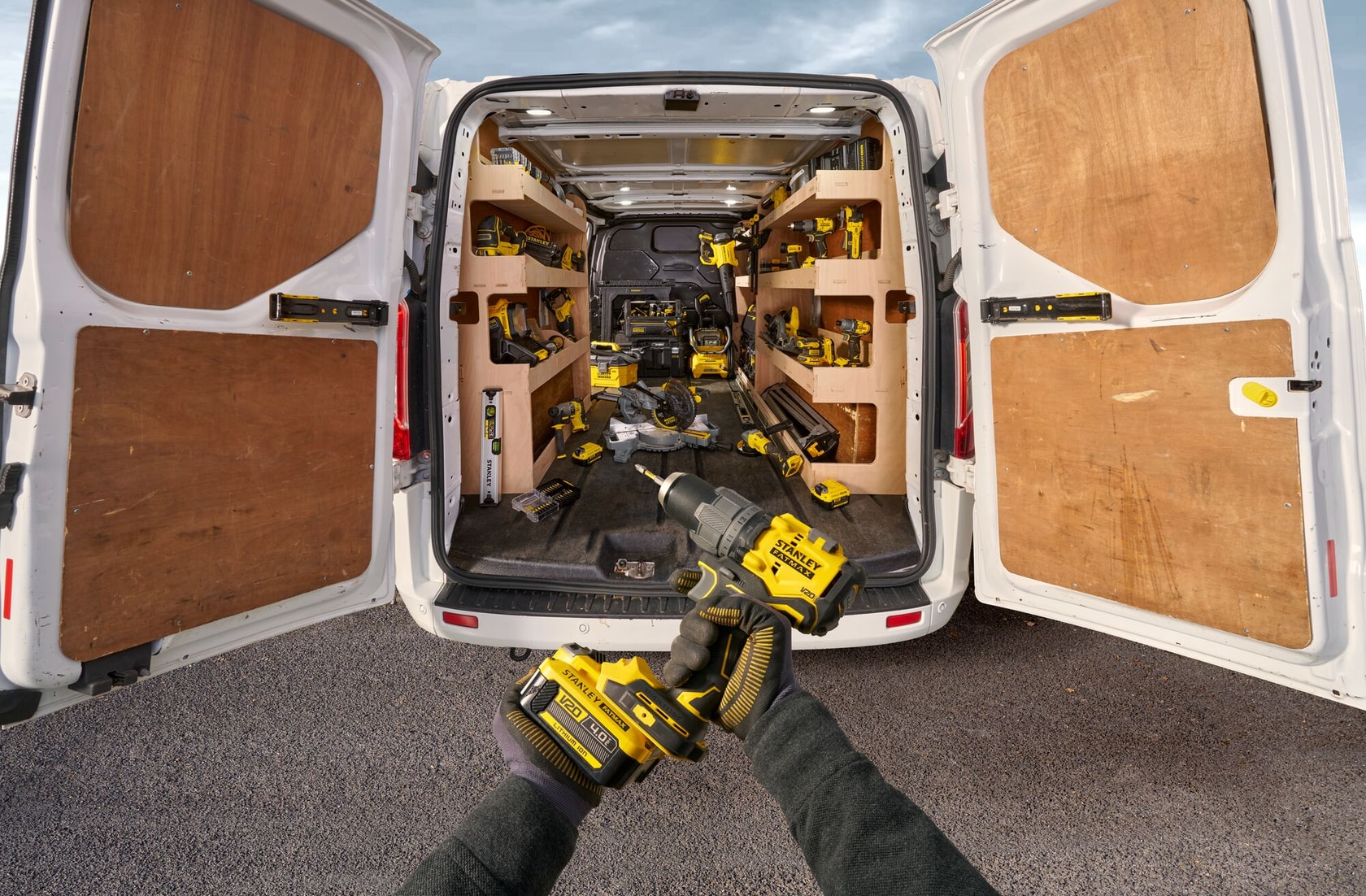 STANLEY gereedschap in het interieur van een bestelwagen, persoon houdt een STANLEY boormachine op de voorgrond, deuren open.